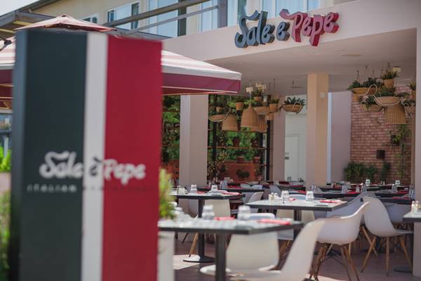 Außenbereich des Sale & Pepe Restaurants mit Tisch und Stühlen, das zur Napa Plaza gehört.