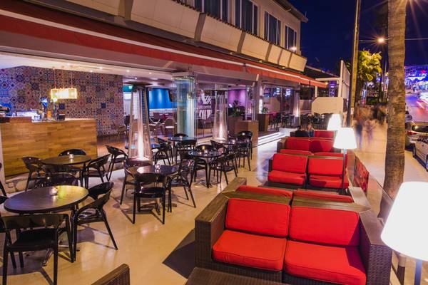 Exterieurbereich des Napa Plaza Hotels bei Nacht mit roten Sofas und Tischen.