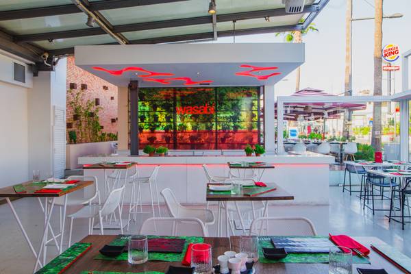 Innenansicht des Restaurants im Napa Plaza Hotel mit grünen Pflanzen und roten Neonschriftzug.