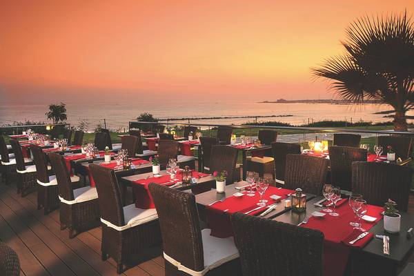 Alexander The Great Hotel Terrasse mit eingerichteten Tischen und Blick auf den Ozean bei Sonnenuntergang