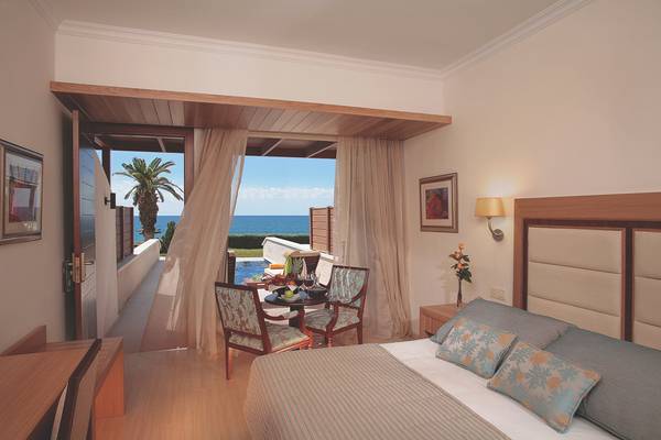 Zimmer im Alexander The Great Hotel mit Meerblick, Balkon und Tisch mit Obst und Wein.