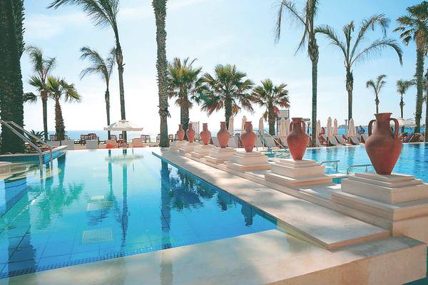 Außenpool des Alexander The Great Hotels mit blauem Wasser und roten Vasen.