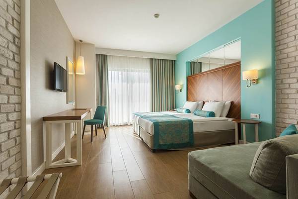 Hotelzimmer im Terrace Elite Resort mit Doppelbett, Sofa, Fernseher und Schreibtisch.