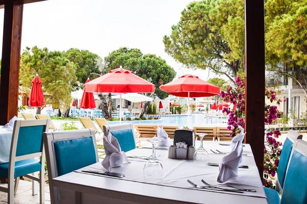 Ein Tisch im Restaurant mit roten Sonnenschirmen und Blick auf den Swimmingpool.