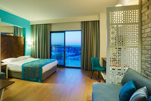 Terrace Elite Resort Hotelzimmer mit Bett, Sofas, Tisch und Glastür mit Stadtblick.