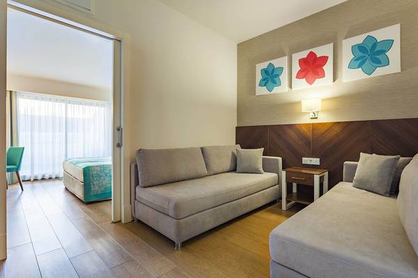 Schlafzimmer im Terrace Elite Resort mit zwei Sofas, Nachttisch und drei Wandbildern.