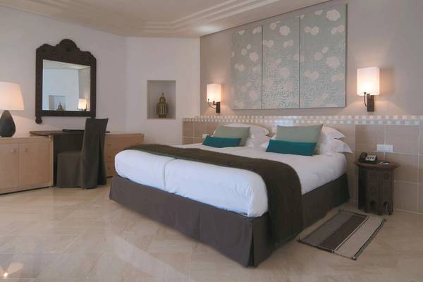 Schlafzimmer im Radisson Blu Palace Resort & Thalasso, Djerba mit zwei Betten, Nachttischen und Wandleuchten.