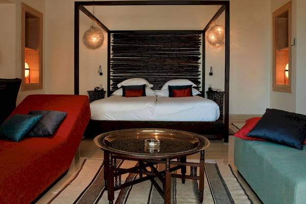 Schlafzimmer im Radisson Blu Palace Resort & Thalasso, Djerba, mit einem großen Bett, einem Tisch und zwei Liegen.