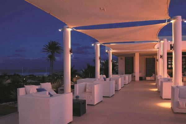 Terrasse des Radisson Blu Palace Resorts bei Nacht mit weißen Möbeln und Palmen im Hintergrund.