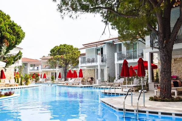 Außenansicht des Swimmingpools des Selectum Family Comfort Side Hotels mit Sonnenliegen und roten Sonnenschirmen.