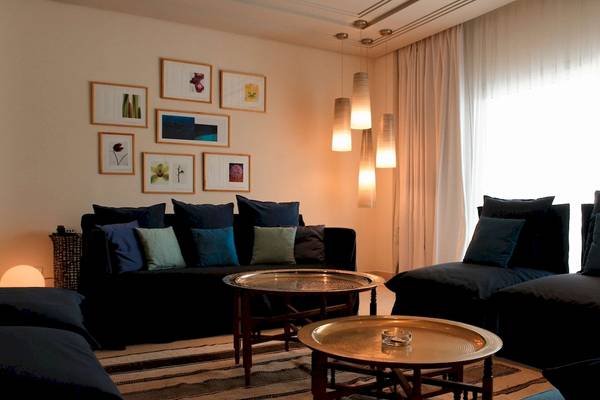 Wohnbereich im Radisson Blu Palace Resort & Thalasso, Djerba mit schwarzen Sofas und goldenen Tischen.