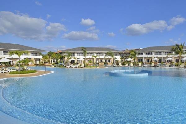 Paradisus Princesa del Mar Resort & Spa Pool-Ansicht mit Gebäuden, Liegestühlen und Palmen.