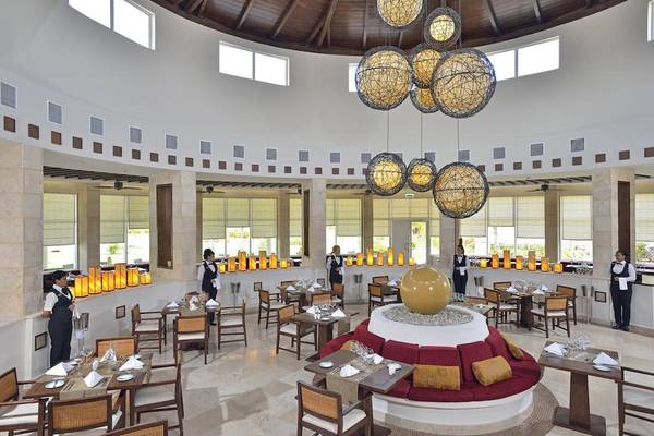 Innenansicht des Restaurants im Paradisus Princesa del Mar Resort & Spa mit runden Leuchten und gedeckten Tischen.