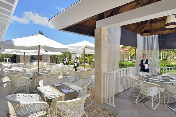 Außenbereich des Paradisus Princesa del Mar Resort & Spa mit weißen Stühlen, Tischen und Sonnenschirmen.