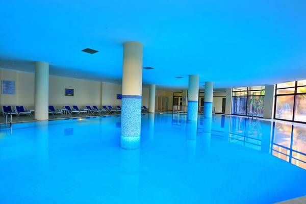 Ein großer Swimmingpool im Selectum Family Comfort Side Hotel mit blauer Beleuchtung und Loungestühlen.