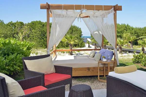 Gartenloungebereich des Paradisus Princesa del Mar Resort & Spa mit einem Bett und Stühlen.