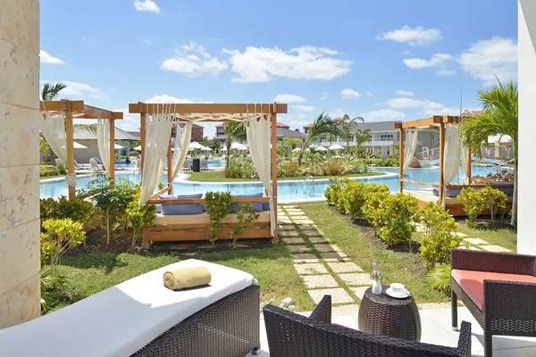 Außenbereich des Paradisus Princesa del Mar Resort & Spa mit Loungebetten, einem Swimmingpool und üppiger Vegetation.