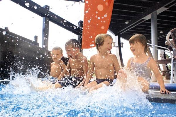Vier Kinder sitzen im Pool und spielen vergnügt im Wasser.