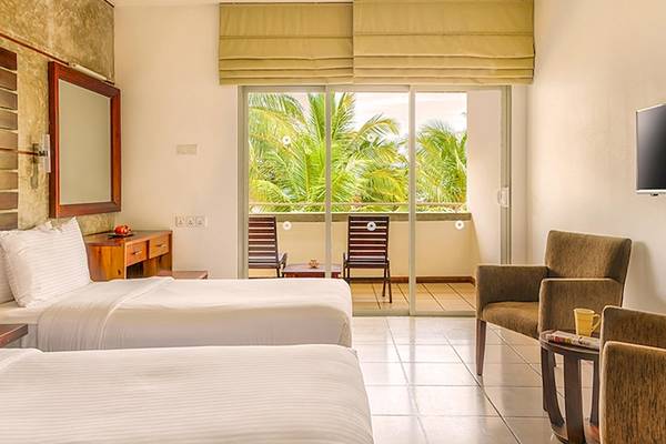 Doppelzimmer im Jetwing Sea Hotel mit Blick auf einen Balkon und zwei Betten