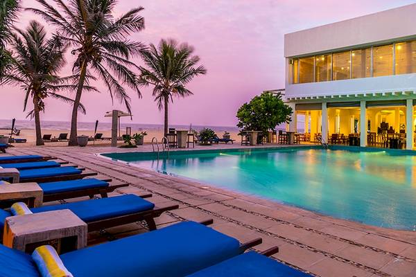 Am Abendansicht des Jetwing Sea Hotels mit Swimmingpool und Loungestühlen.