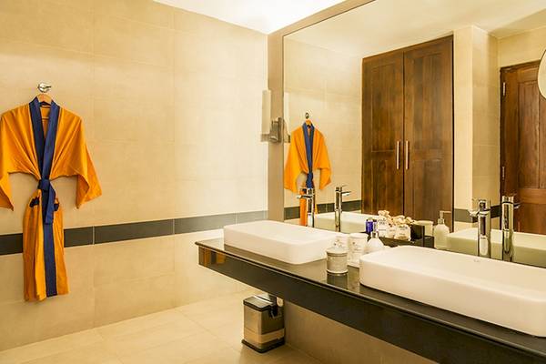 Badezimmer im Jetwing Sea Hotel mit zwei Waschbecken, Spiegel und gelben Kimonos