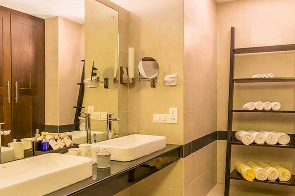 Badezimmer des Jetwing Sea Hotels mit zwei Waschbecken, Spiegel und Regal mit Handtüchern.