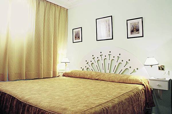 Doppelbett im Hotelzimmer des Rey Carlos mit drei Bildern an der Wand