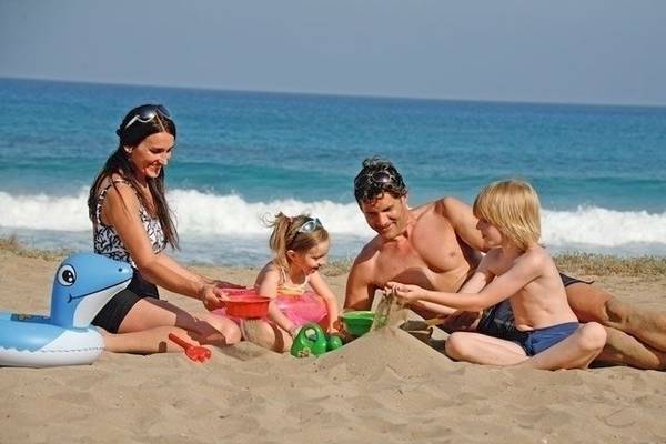 Eine Familie am Strand mit Kindern und Meer im Hintergrund.