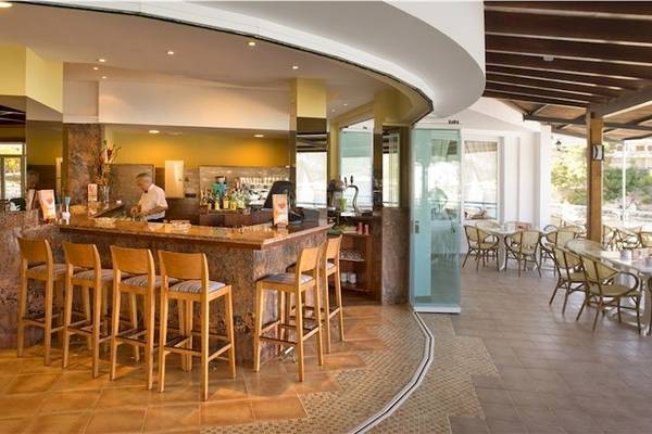 Rezeption im Universal Hotel Aquamarin mit Bar, Holzstühlen und Tischen draußen.