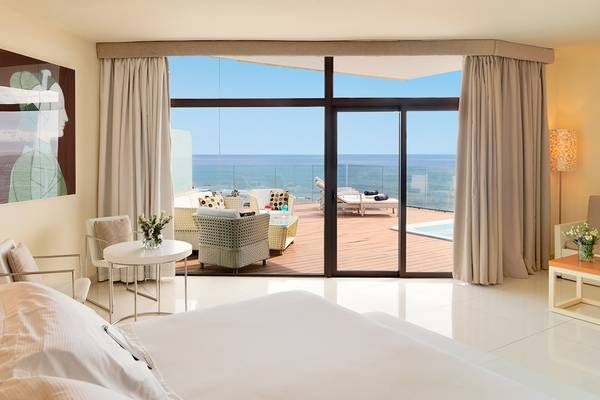 Suite im H10 Conquistador mit Meerblick, großem Bett und Terrassenmöbeln.