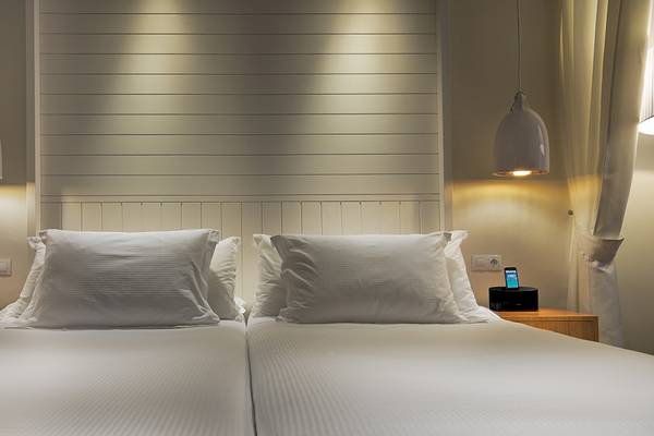 Doppelbettzimmer im H10 Conquistador Hotel mit weißen Laken, Kissen und Lampen.