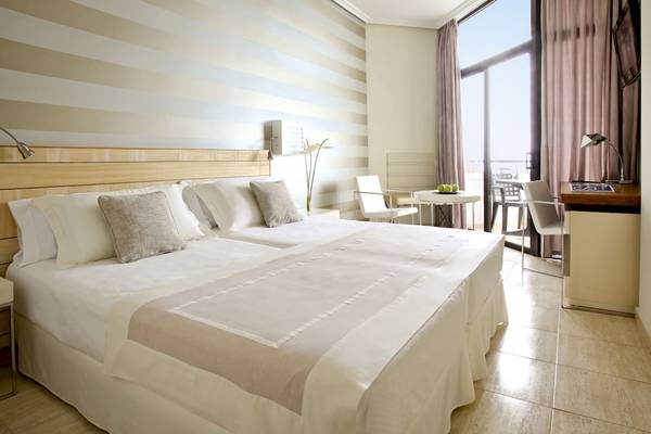 Doppelbett-Zimmer im H10 Conquistador Hotel mit gestreiften Wänden und Blick auf den Ozean.