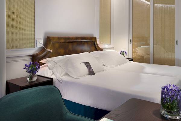 Doppelbett-Zimmer im H10 Conquistador Hotel mit weißen Laken, Kissen und Blumenvasen.