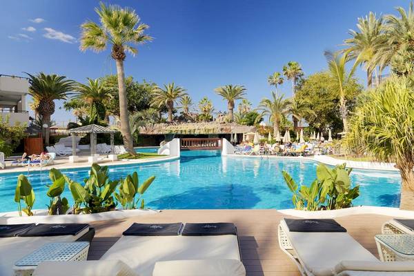 Außenpool und Loungebereich des H10 Conquistador Hotels mit weißen Sonnenliegen und blauem Wasser