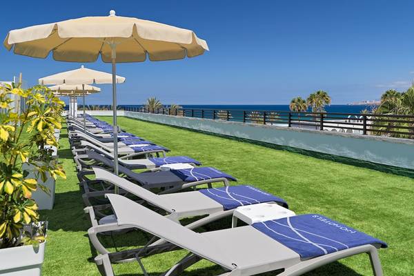 Dachterrasse des H10 Conquistador Hotels mit Sonnenliegen und Sonnenschirmen am Meer