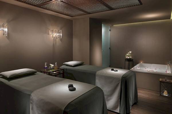 Spa-Behandlungsraum im H10 Conquistador Hotel mit zwei Massageliegen und einer Badewanne.