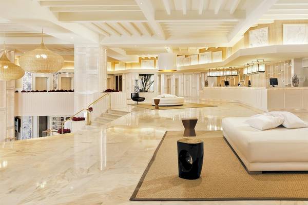 Lobby des H10 Conquistador Hotels mit Marmorboden, weißen Möbeln und hohen Decken.