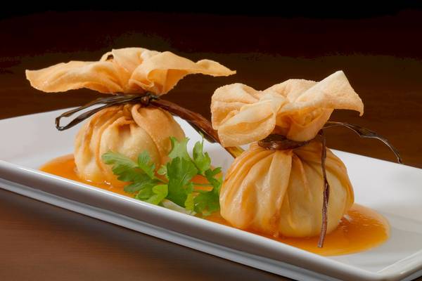 Zwei asiatische Gerichte auf einem weißen Teller mit Sauce und Gewürzen.