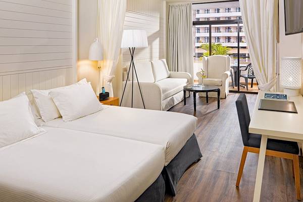Innenansicht eines Doppelzimmers im H10 Conquistador Hotel mit zwei Betten, Schreibtisch und Balkon.