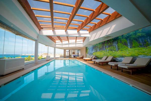 Innenpool des Ramla Bay Resorts mit Panoramafenster und Sonnenliegen
