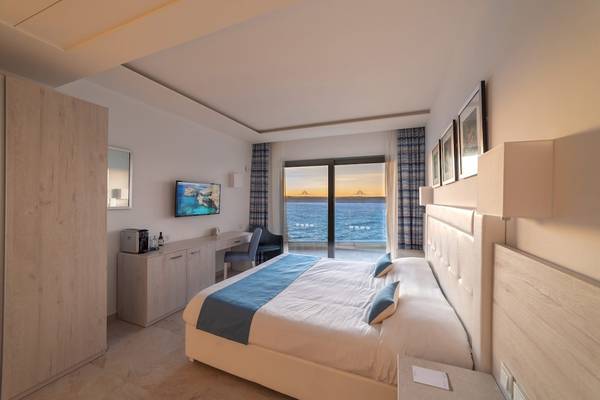 Hotelzimmer im Ramla Bay Resort mit Meerblick, Bett, Schreibtisch und Fernseher.