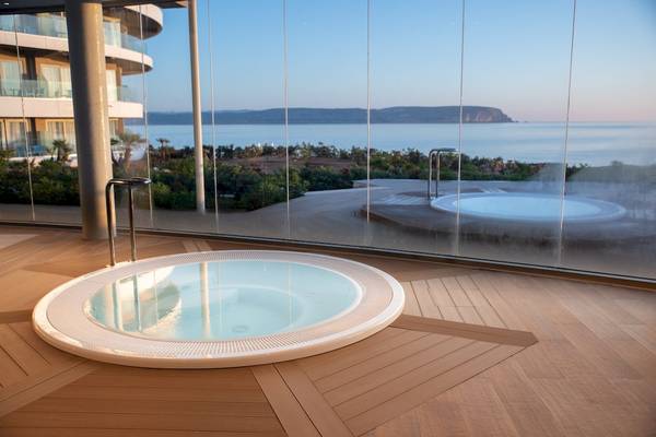 Außenwhirlpool des Ramla Bay Resorts mit Blick auf das Meer und einen Gebäudekomplex.