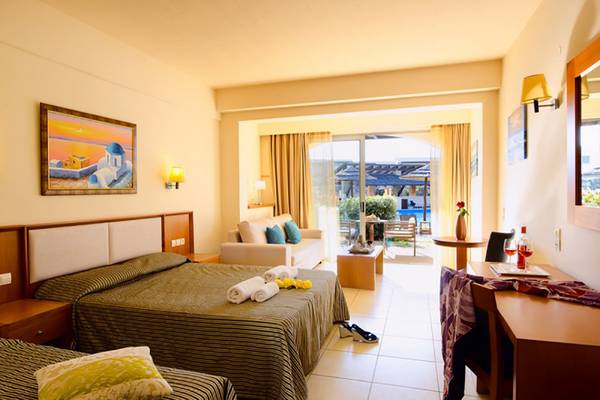 Innenansicht eines Doppelzimmers im Stella Palace Resort & Spa mit zwei Betten, einem Sofa und einer Aussicht auf den Pool.