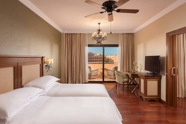 Doppelzimmer mit Balkon im Sheraton Fuerteventura Beach, Golf & Spa Resort mit zwei Betten und Blick auf einen Garten.