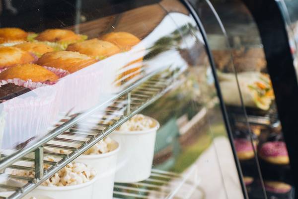 Eine Vitrine mit verschiedenen gebackenen Gütern, einschließlich Muffins, Popcorn und Schokolade, in einer Bäckerei.