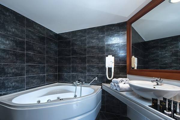 Badezimmer des Stella Palace Resort & Spa mit Badewanne, Waschbecken und Spiegel