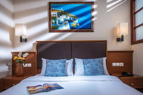 Ein Bett im Stella Palace Resort & Spa mit Bettwäsche, Kissen und einer Zeitschrift auf dem Bett.
