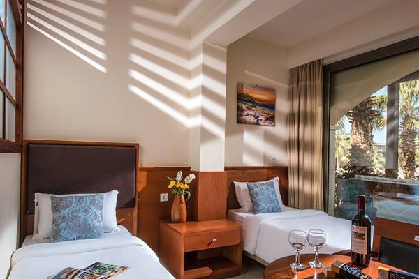 Doppelzimmer im Stella Palace Resort & Spa mit zwei Betten, Tisch und Weinflaschen.