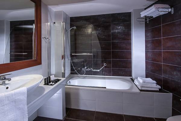 Badezimmer im Stella Palace Resort & Spa mit Badewanne, Dusche und Spiegel