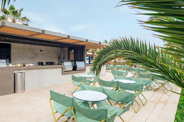 Außenbereich des Stella Palace Resort & Spa mit Café, Tischen und Stühlen.